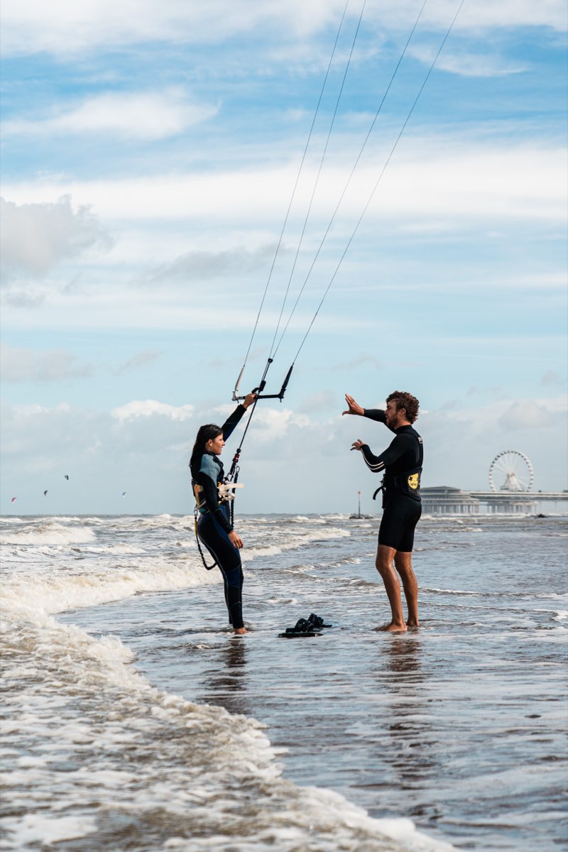 An instructor talking a student through kite control at the waterline